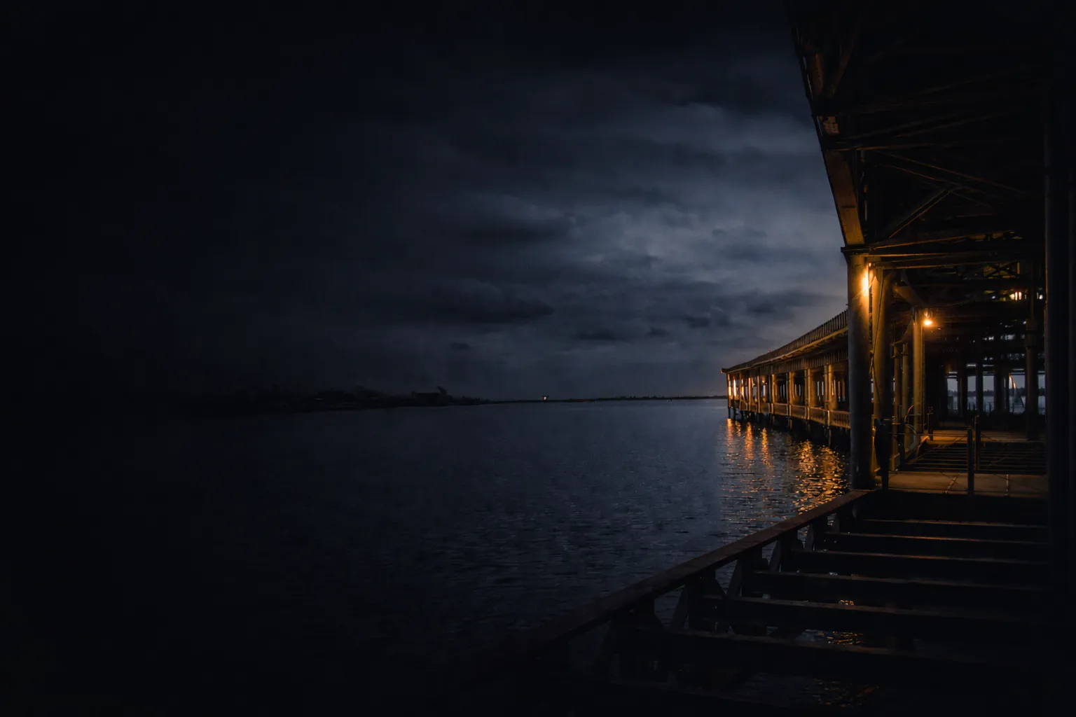 Paisaje oscuro junto al agua con una estructura metálica lateral